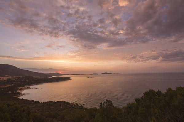 The colors of sunrise are reflected on the sea around the beach of Solanas Villasiumus Cagliari Sardinia Italy Europe