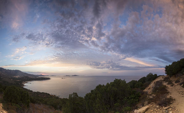 The colors of sunrise are reflected on the sea around the beach of Solanas Villasiumus Cagliari Sardinia Italy Europe