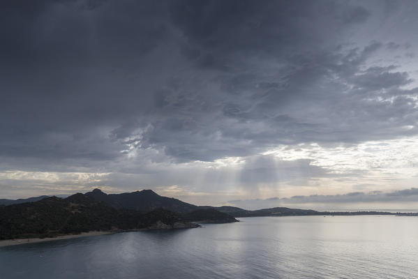 The sunbeams between clouds are reflected on the blue sea Solanas Villasimius Cagliari Sardinia Italy Europe