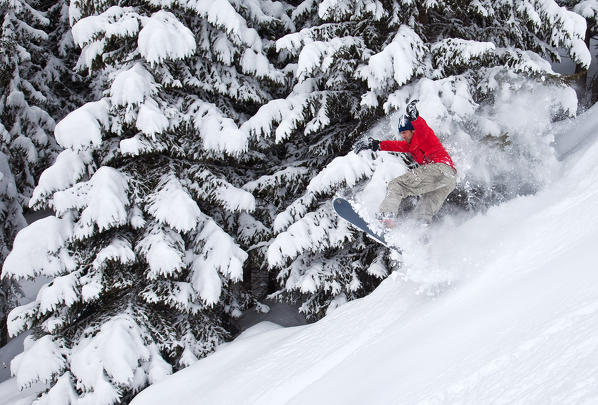 A snowboarder jumping in the snow of the Orobie Alps, Lombardy, Valtellina, Italy Europe