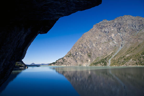 A rock is the perfect frame for the Sasso Moro, which is reflecting in the artificial lake of Alpe Gera in Valmalenco, Lombardy Italy. Europe