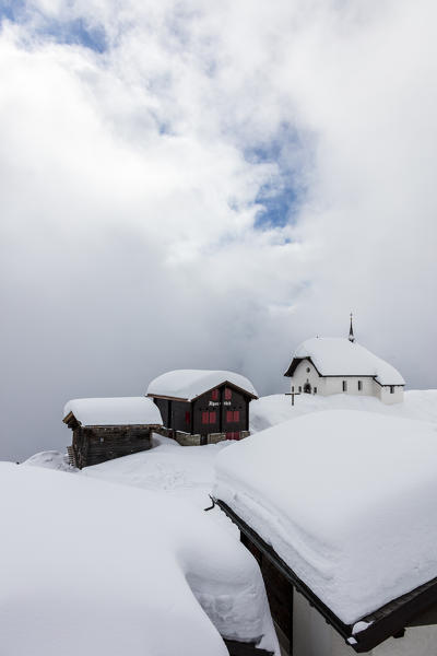 Snow covered mountain huts and church surrounded by low clouds Bettmeralp district of Raron canton of Valais Switzerland Europe