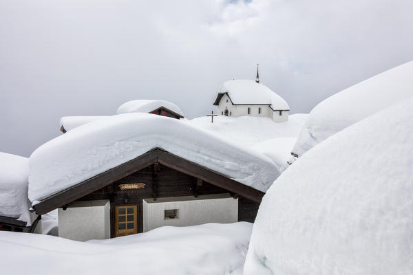 Snow covered mountain huts and church surrounded by low clouds Bettmeralp district of Raron canton of Valais Switzerland Europe