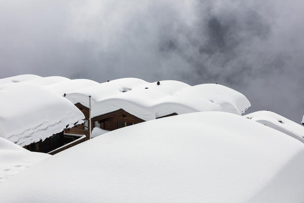 Snow covered mountain huts surrounded by low clouds Bettmeralp district of Raron canton of Valais Switzerland Europe