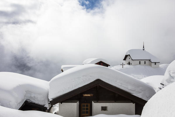 Snow covered mountain huts and church surrounded by low clouds Bettmeralp district of Raron canton of Valais Switzerland Europe