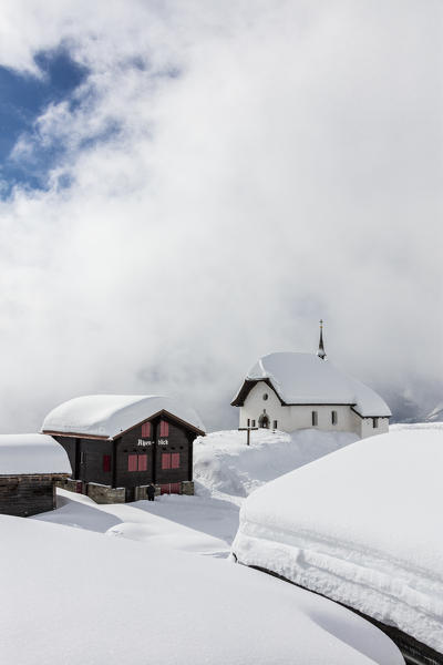 Snow covered mountain huts and church surrounded by clouds Bettmeralp district of Raron canton of Valais Switzerland Europe