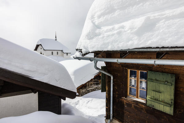 The alpine church surrounded by mountain huts immersed in snow Bettmeralp district of Raron canton of Valais Switzerland Europe