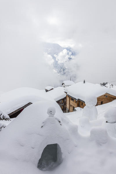 Clouds on the snowman and the mountain huts covered with snow Bettmeralp district of Raron canton of Valais Switzerland Europe