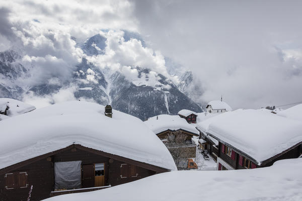 Clouds frame the mountain huts covered with snow Bettmeralp district of Raron canton of Valais Switzerland Europe