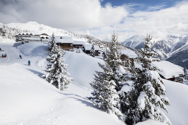 Skiers frame the typical alpine village immersed in snow Bettmeralp district of Raron canton of Valais Switzerland Europe