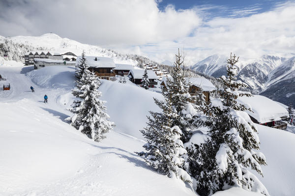 Skiers frame the typical alpine village immersed in snow Bettmeralp district of Raron canton of Valais Switzerland Europe