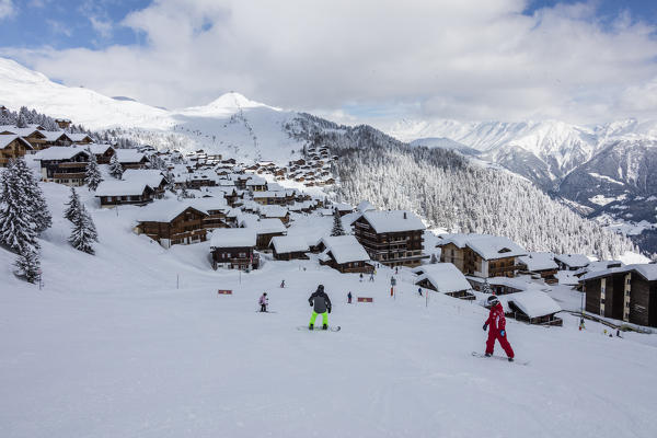 Snowboarders on ski slopes frames the typical alpine village Bettmeralp district of Raron canton of Valais Switzerland Europe