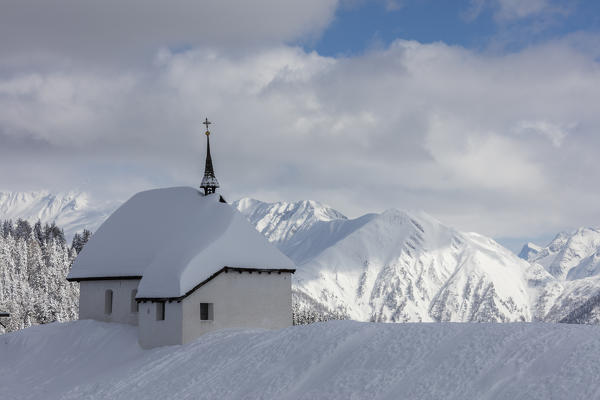 The alpine church immersed in snow frames the high peaks Bettmeralp district of Raron canton of Valais Switzerland Europe