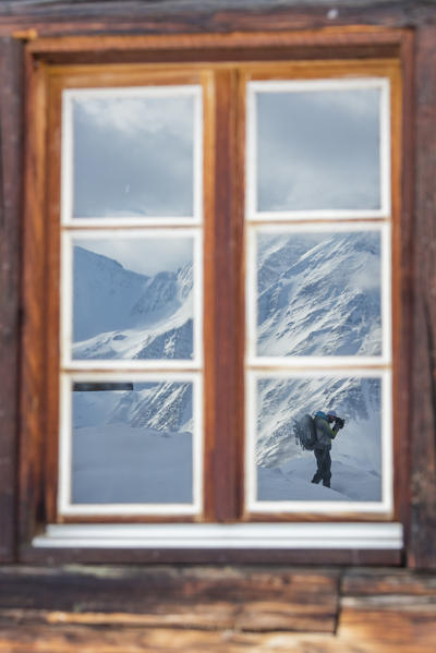The photographer is reflected by window of the wooden hut Bettmeralp district of Raron canton of Valais Switzerland Europe