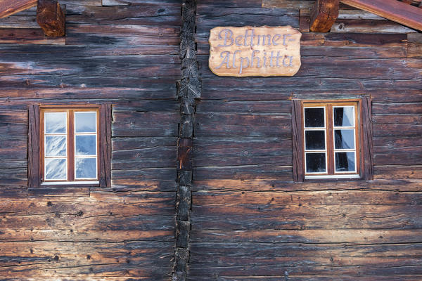 Snowy peaks are reflected into the windows of the wooden hut Bettmeralp district of Raron canton of Valais Switzerland Europe