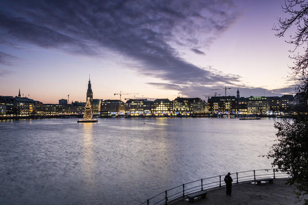 The colors and lights of dusk on Inner Alster Lake with the Christmas Tree suspended in its water Hamburg Germany Europe