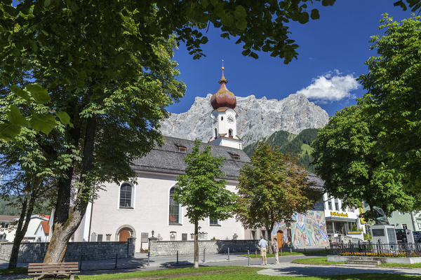 Typical church of alpine village surrounded by peaks and woods Garmisch Partenkirchen Oberbayern region Bavaria Germany Europe