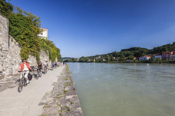 Tourists on bicycles discovering the old buildings and proceed along the banks of the river Passau Lower Bavaria Germany Europe