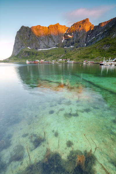 Midnight sun on fishing village surrounded by clear sea and peaks Reine Nordland county Lofoten Islands Northern Norway Europe