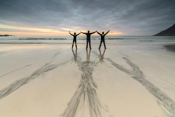 Friends on the beach admire the midnight sun Skagsanden Ramberg Nordland county Lofoten Islands Northern Norway Europe