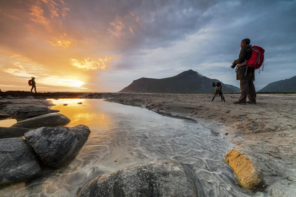 Midnight sun frames photographers in action on Skagsanden beach Ramberg Nordland county Lofoten Islands Northern Norway Europe