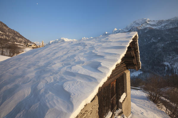 Snowy mountain hut framed by blue sky Soglio canton of Graubünden Maloja District Bregaglia Valley Engadine Switzerland Europe