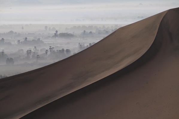 Dunes in the Peru desert and oasis wrapped in the fog in the distance South America