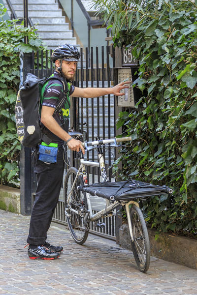Urban bike messenger and delivery at work in the old town center of Milan Lombardy Italy Europe
