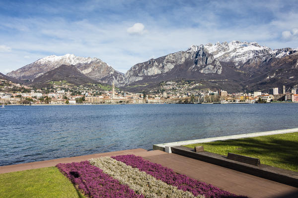 Gardens and flowers at spring frame Lake Como and the city of Lecco with snowy peaks in the background Lombardy Italy Europe
