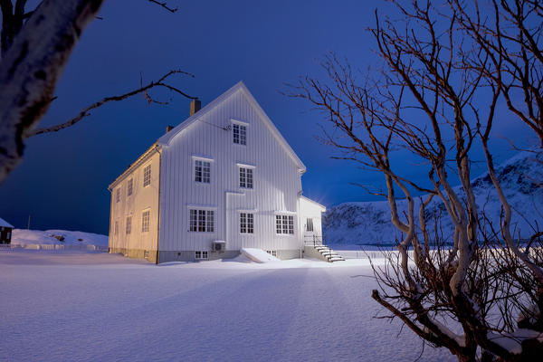 Lights on the typical wooden house surrounded by snow Flakstad Lofoten Islands Northern Norway Europe