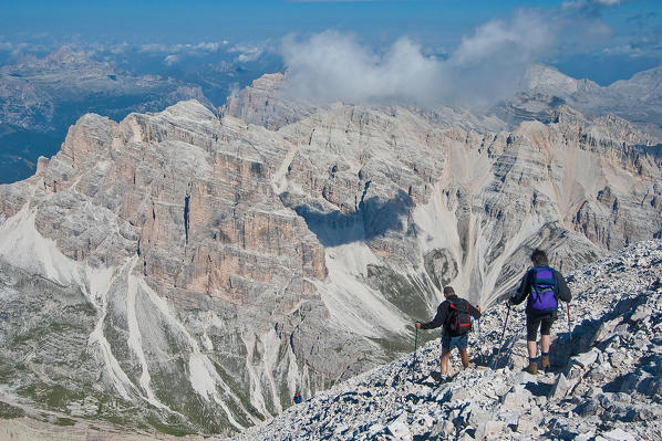 Two hikers descending from the top of the Tofana di Rozes. In the background the Lagazuoi group Dolomites, Trentino Alto Adige Italy Europe
