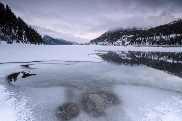 Cloudy sky at sunrise on the frozen Lake Champfer surrounded by snow St.Moritz Canton of Graubunden Engadine Switzerland Europe