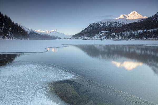 Snowy peaks reflected in the frozen Lake Champfer at dawn St.Moritz Canton of Graubunden Engadine Switzerland Europe