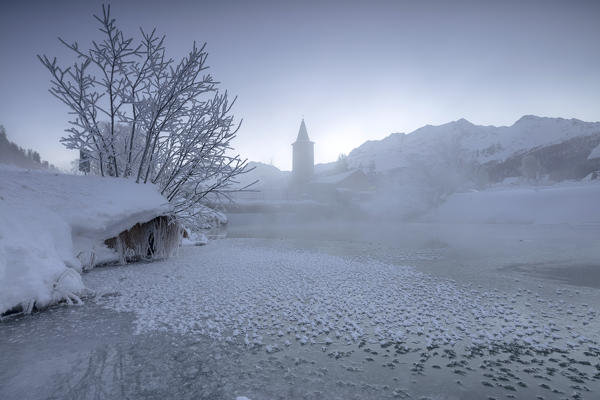 The frozen river Inn framed by mist and snow at dawn Sils Canton of Graubunden Engadine Switzerland Europe