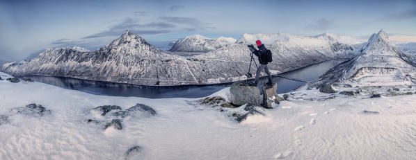 Panorama of photographer on snowy peak surrounded by the frozen sea at sunset Gryllefjorden Senja Troms County Norway Europe