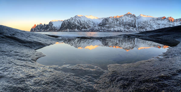 Panorama of the snowy peaks reflected in the cold sea at sunset Tungeneset Senja Troms County Norway Europe