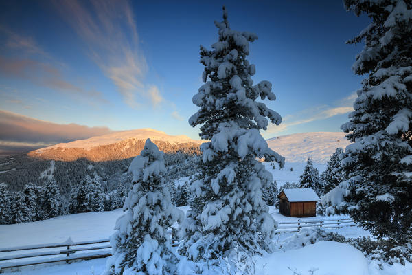 The sunrise lights up the snowy woods and hut Passo Delle Erbe Funes Valley South Tyrol Italy Europe