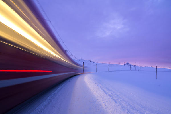 Bernina Express train runs fast in the snowy landscape at dawn Bernina Pass Canton of  Graubünden Engadine Switzerland Europe