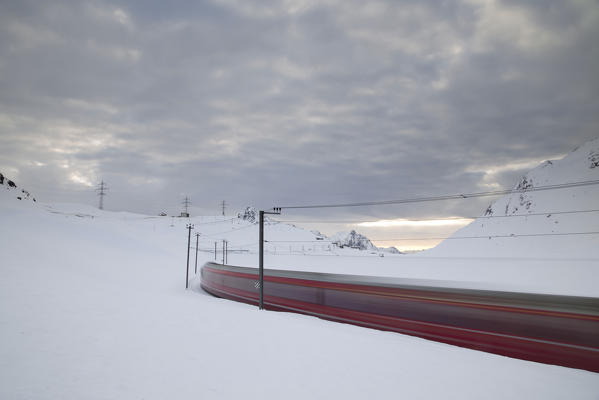 Bernina Express train runs fast in the snowy landscape at dawn Bernina Pass Canton of  Graubünden Engadine Switzerland Europe