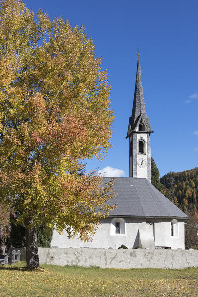 The colors of the autumnal tree frame the old alpine church of Cinuos-Chel Canton of Graubünden Engadine Switzerland Europe