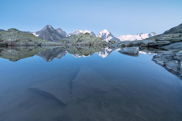 Snowy peaks are reflected in the alpine lake at dusk Fuorcla Surlej St. Moritz Canton of Graubünden Engadine Switzerland Europe