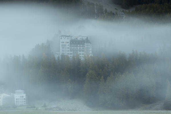 Mist of the autumn dawn surrounds the woods and the landscape of Sils the Canton of Graubünden Engadine Switzerland Europe