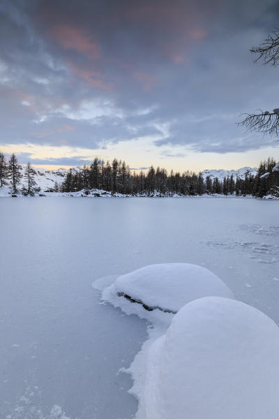 The pink clouds frame the frozen Lago Azzurro at dawn Spluga Valley Province of Sondrio Valtellina Lombardy Italy Europe