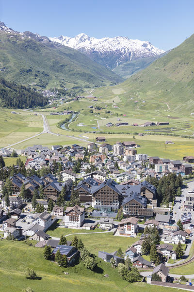 The alpine village of Andermatt surrounded by green meadows and snowy peaks in the background Canton of Uri Switzerland Europe