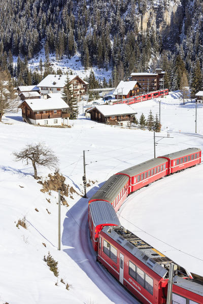 Red train of Rhaetian Railway passes in the snowy landscape of Arosa district of Plessur Canton of Graubünden Switzerland Europe