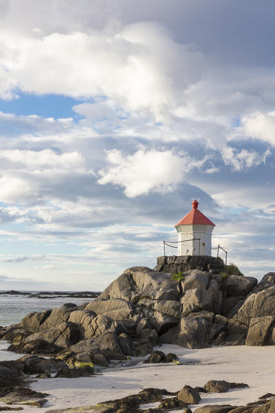 Midnight sun lights up lighthouse on cliffs surrounded by turquoise sea  Eggum Unstad Vestvagøy Lofoten Islands Norway Europe