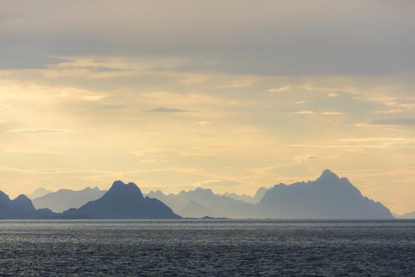 Midnight sun lights up the rocky peaks overlooking the clear sea Lofoten Islands Norway Europe