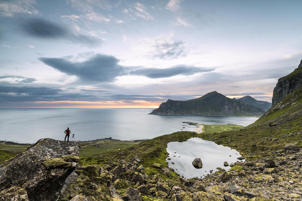 Photographer admires clouds of midnight sun on the cold sea Flakstad Moskenesøya Nordland county Lofoten Islands Norway Europe