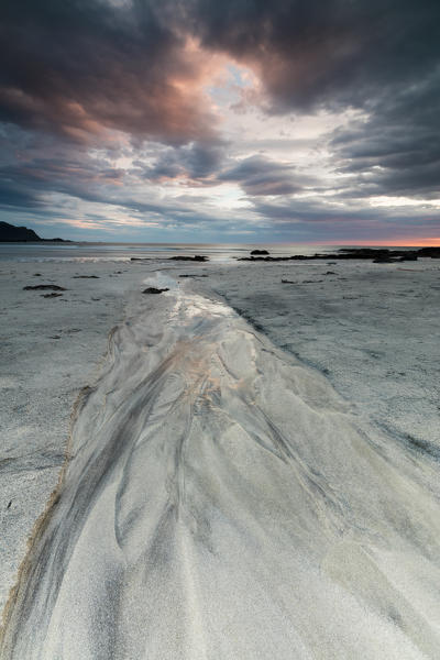 Midnight sun and clouds frame the sandy beach of Skagsanden Flakstad Nordland county Lofoten Islands Norway Europe