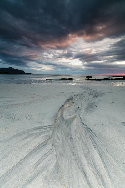 Midnight sun and clouds frame the sandy beach of Skagsanden Flakstad Nordland county Lofoten Islands Norway Europe